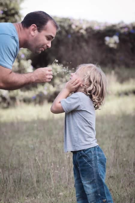 child and dad blowing dandelions