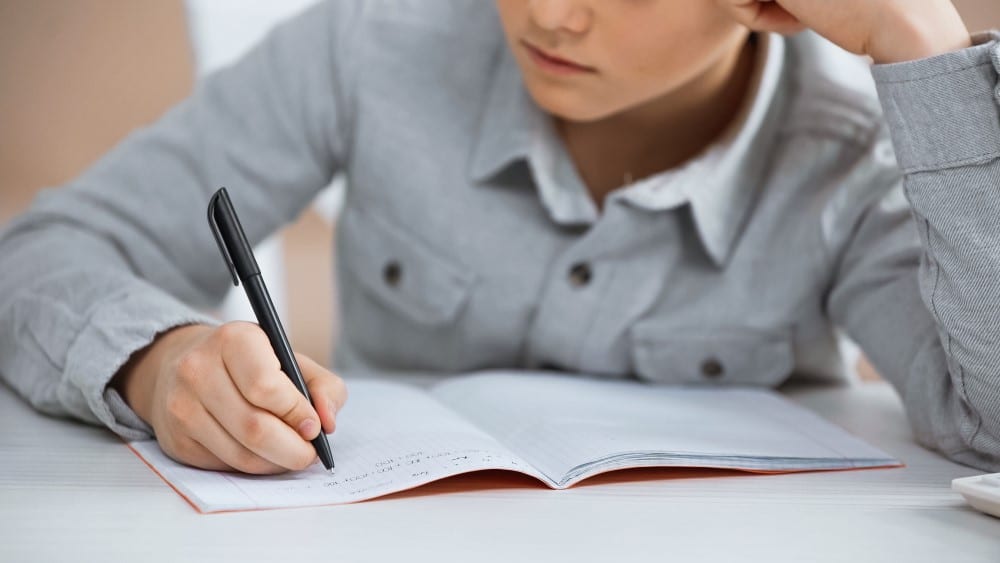 homeschool writing curriculum - boy writing on notebook