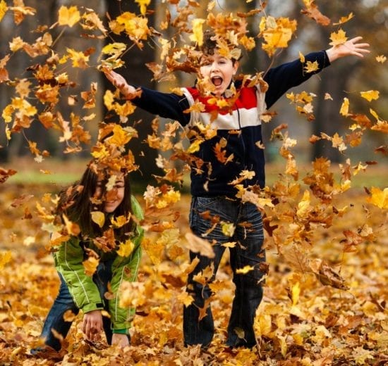 Children throwing fall leaves