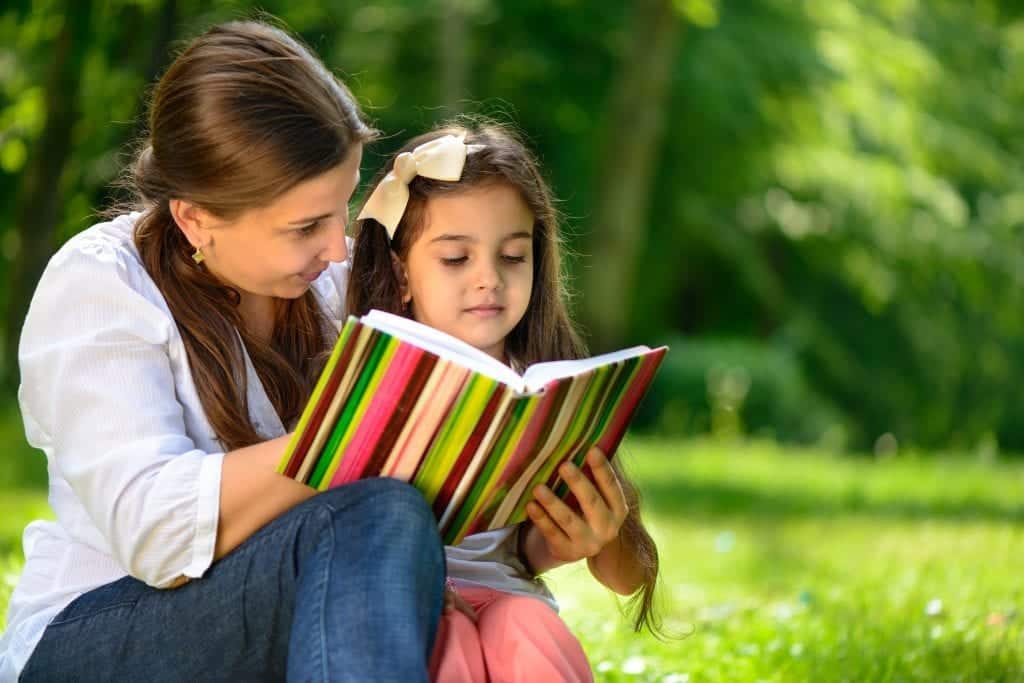 Happy family reading book at park