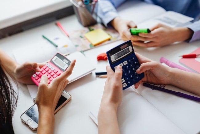 math activities - calculators in children's hands, with note pads and pens at a table