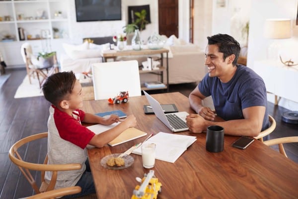 homeschool dad laughing with son at table