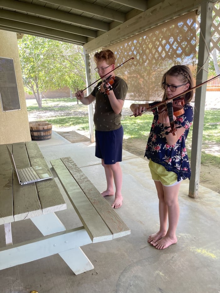 The Suzuki Method - two children practicing violin out on a patio
