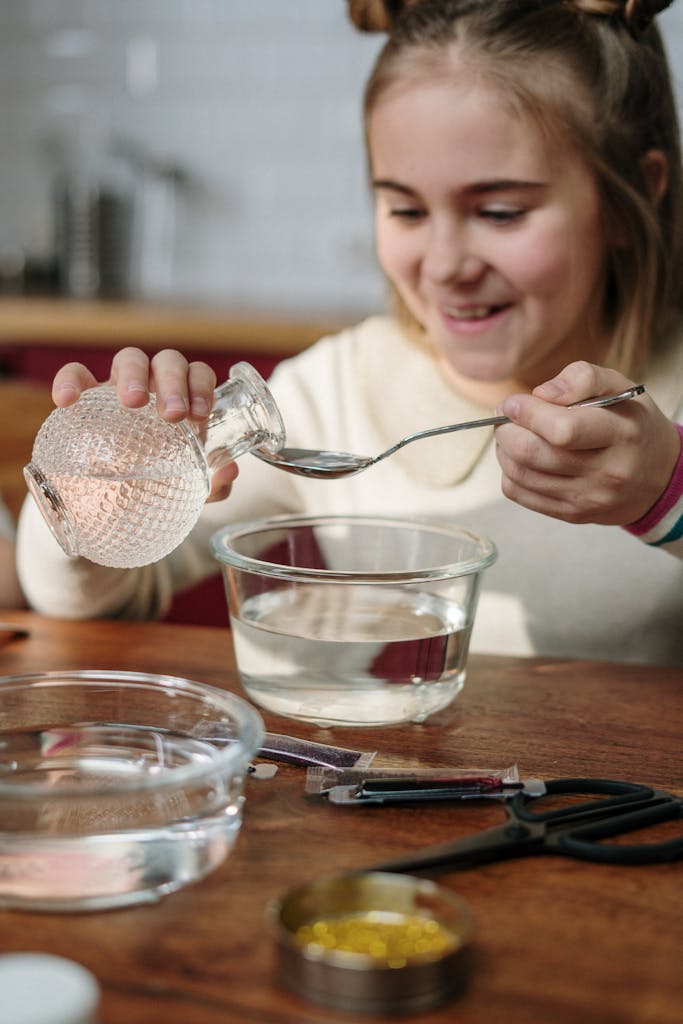 Young girl happily conducting a water-based experiment at a wooden table.