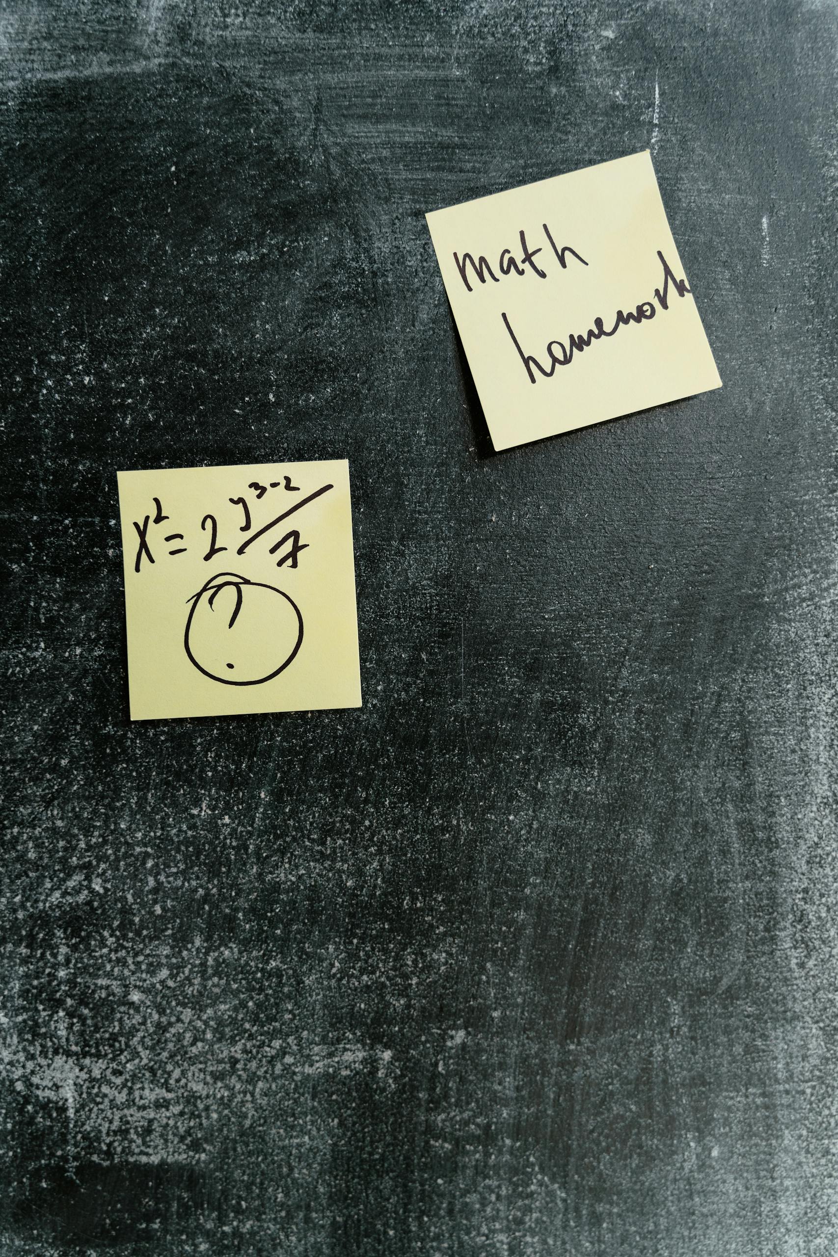 Sticky notes with math equations and homework reminders on a chalkboard.