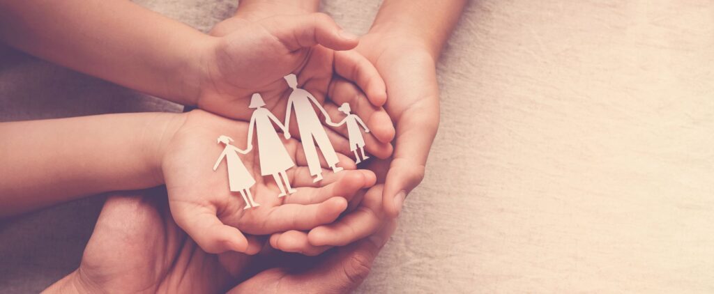 family hands holding paper cut out of a family