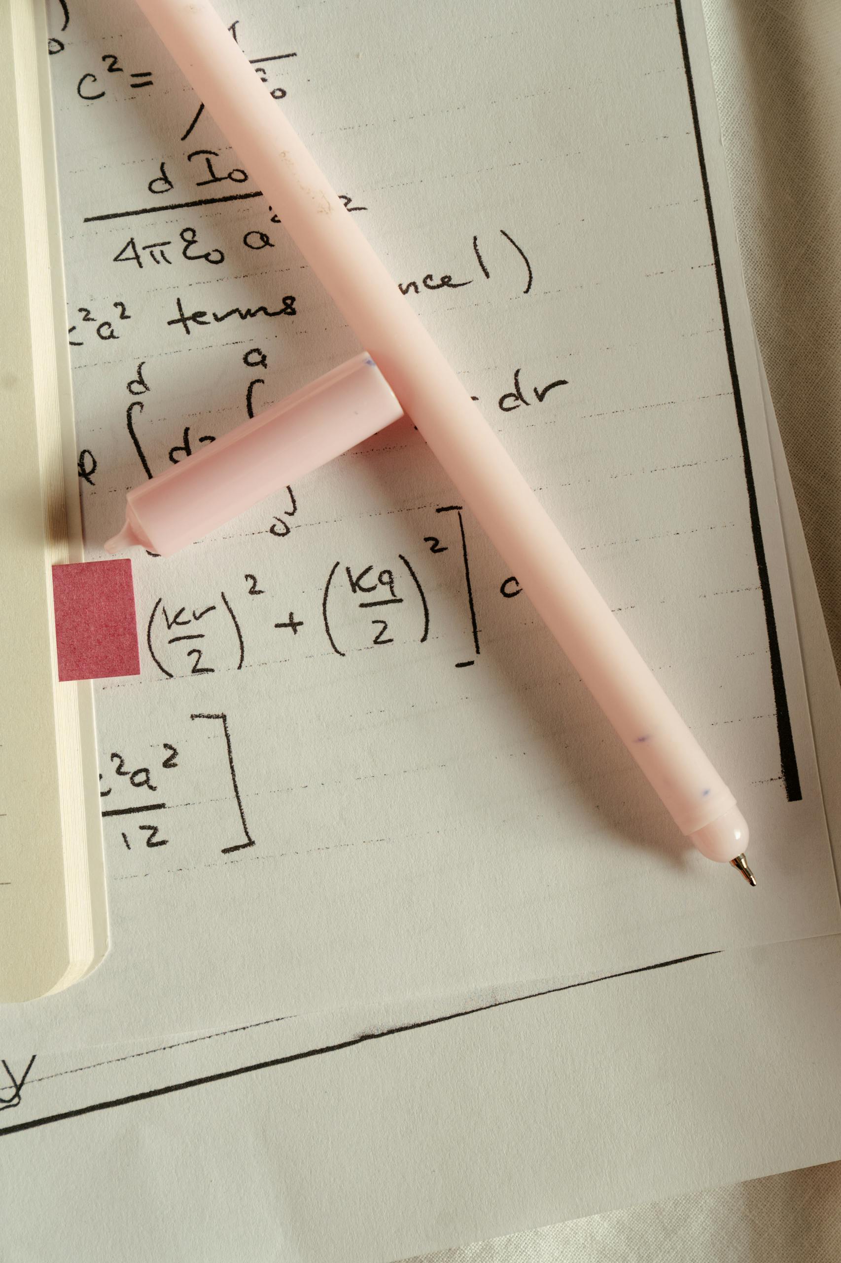 Overhead view of mathematical equations on paper with a pink pen, perfect for education and study concepts.